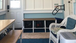 A room with a ceiling fan, a painting of a beach scene, a white wicker chair, a wooden table, and a blue carpet. - 4 Nights Left -Perfect Family-Friendly Condo 5 Houses from the Ocean-Beach Block (Dewey Beach)
