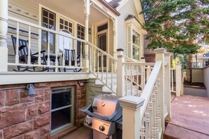 Una casa con porche, una parrilla y una escalera.