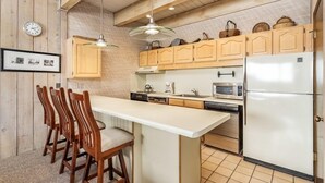 Una cocina con armarios de madera, una isla blanca y un microondas.