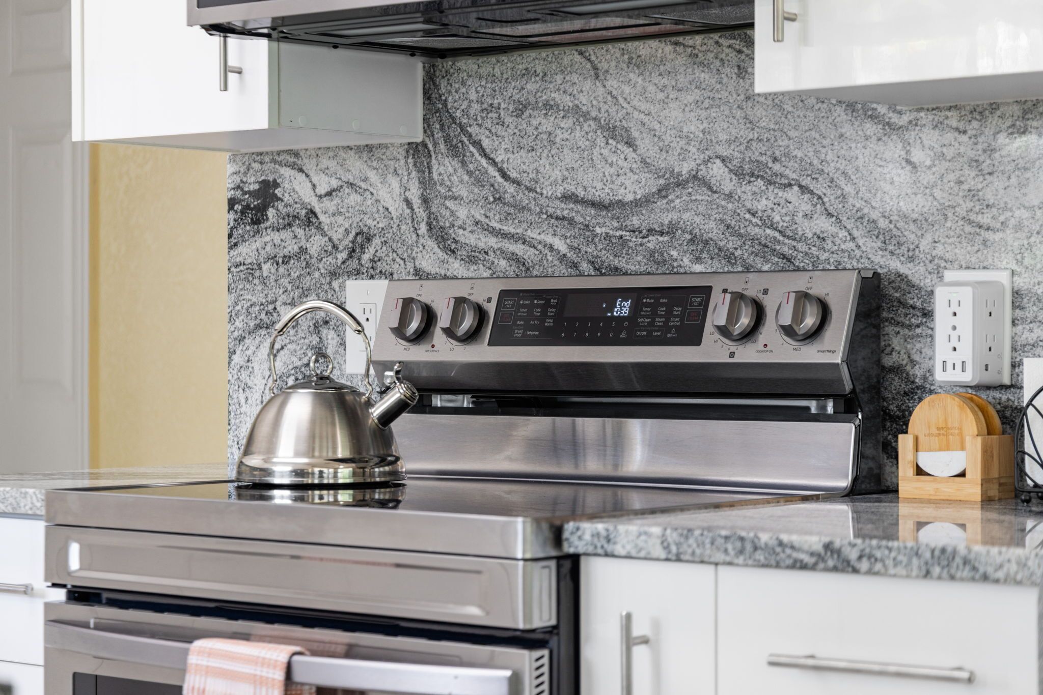 A kitchen with a stainless steel stove, a kettle, and a built-in oven.