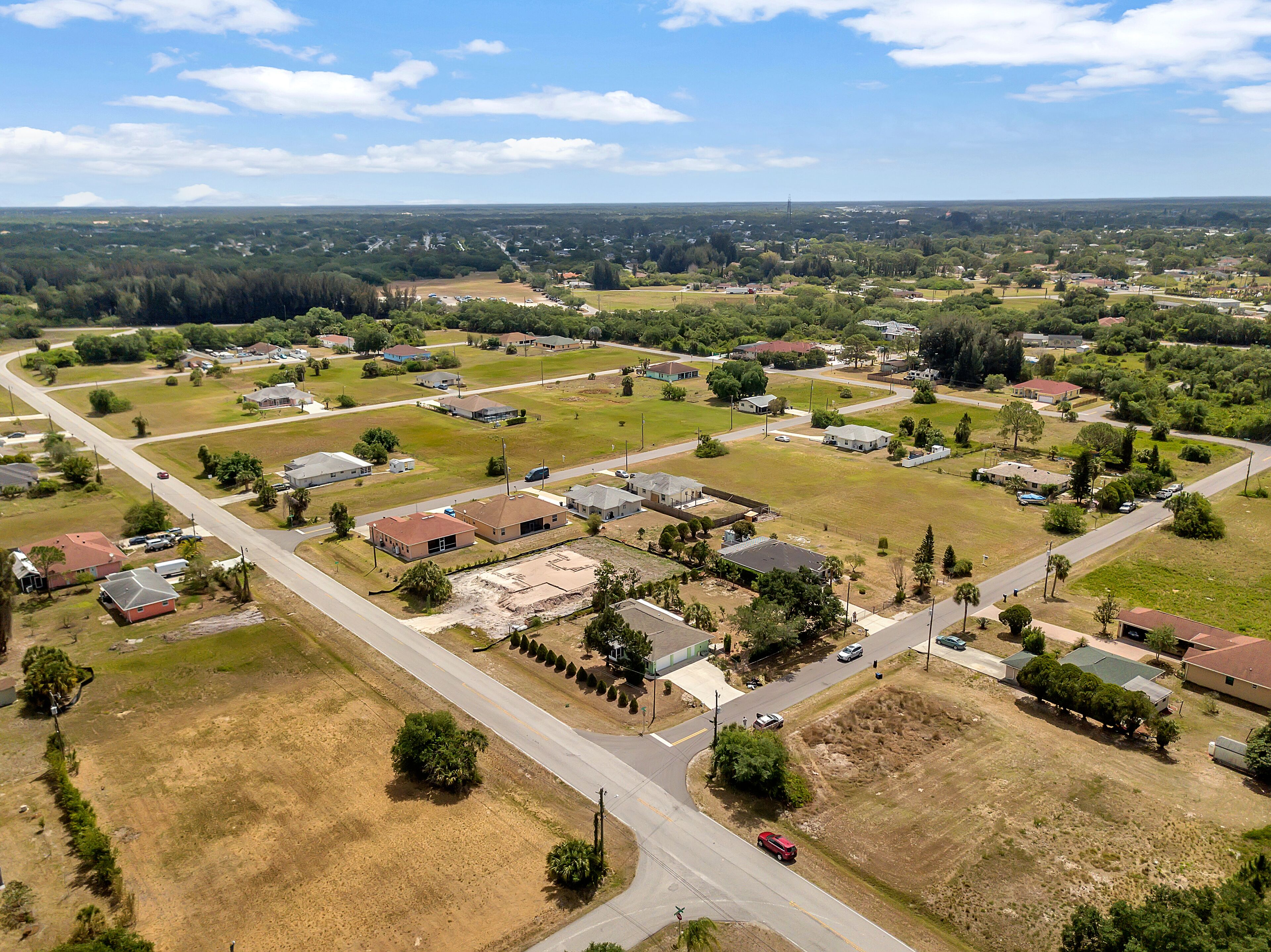 An aerial view of a residential area with houses, roads, and green spaces.