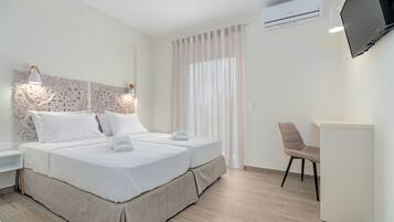 Ein Hotelzimmer mit zwei Betten, einem an der Wand befestigten Fernseher, einem Schreibtisch und einem Stuhl.