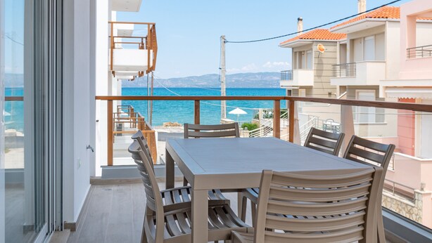 A balcony with a dining table and chairs, overlooking a coastal view. - COSTAVASIA Apartments (Velo-Vocha)