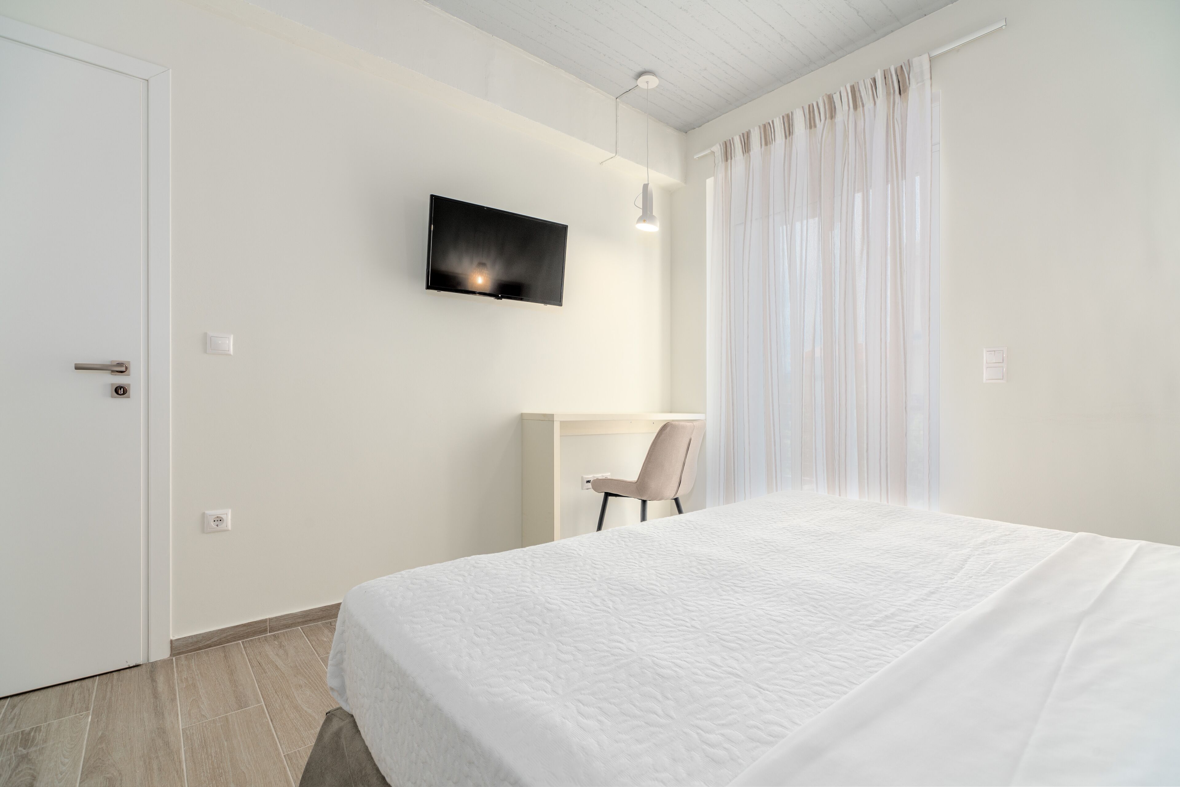 Una habitación de hotel moderna con una cama grande, un escritorio y un televisor montado en la pared.