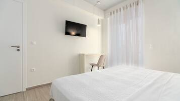 Una habitación de hotel moderna con una cama grande, un escritorio y un televisor montado en la pared.
