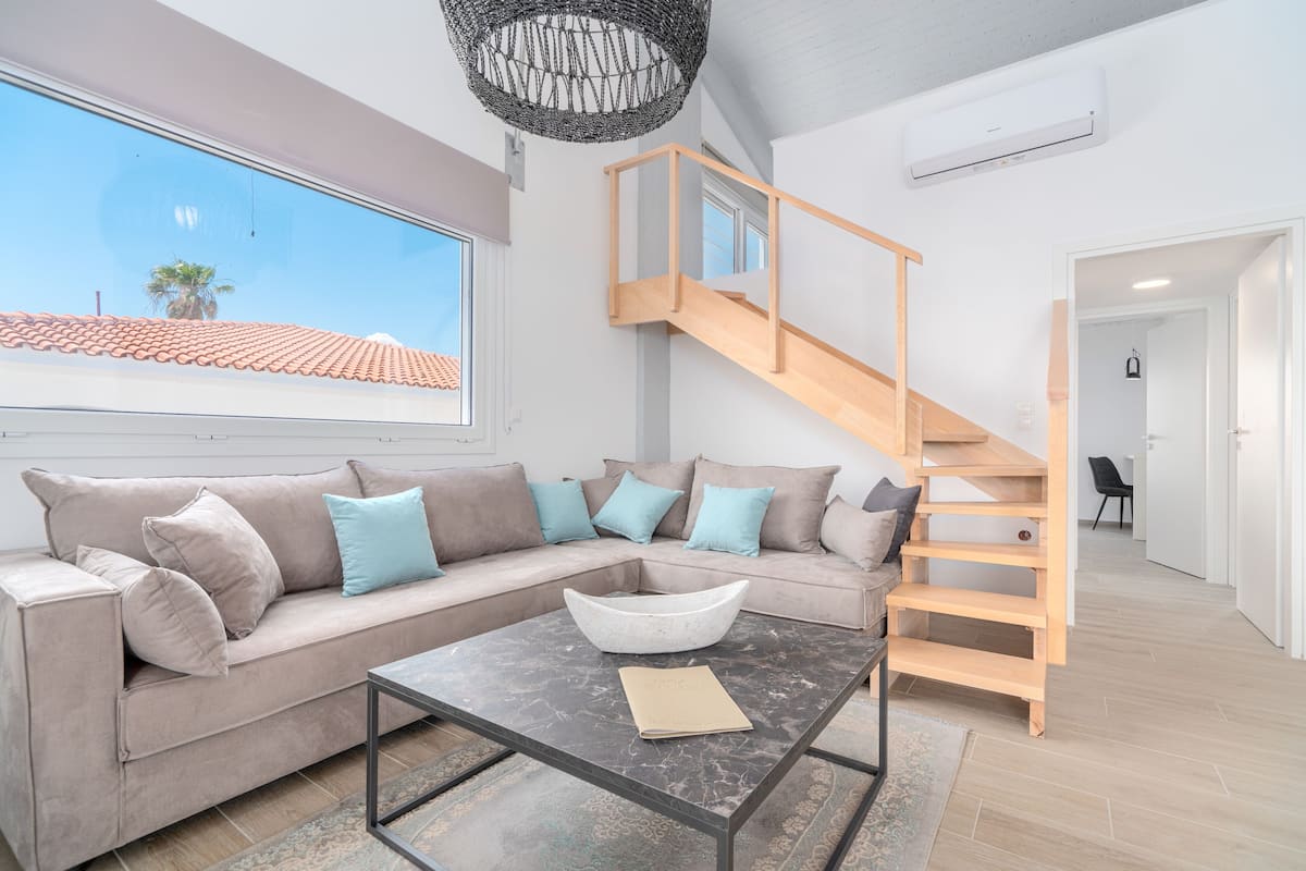A modern living room with a sofa, coffee table, and a staircase leading to an upper level.