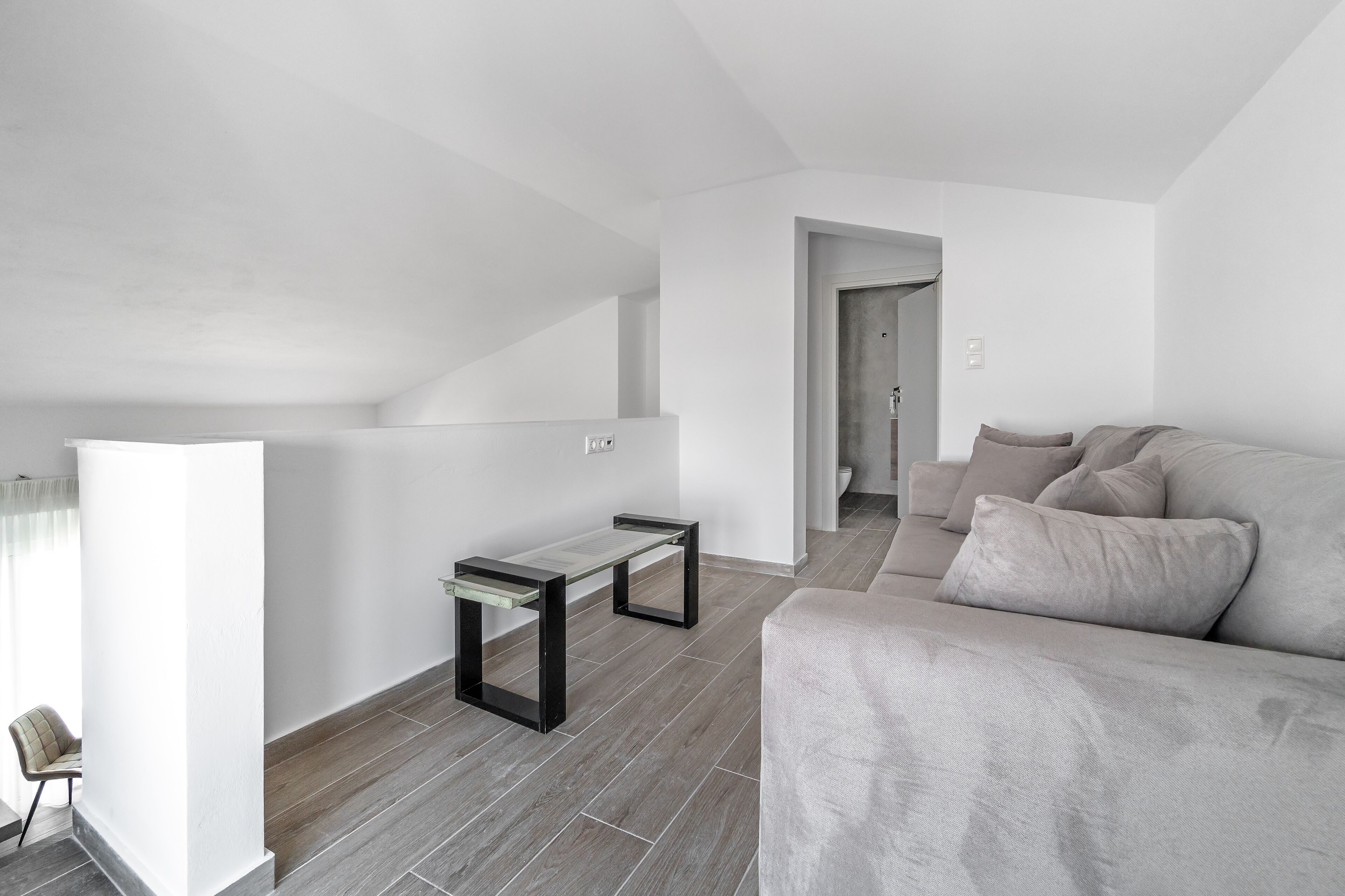 A modern living room with a grey sofa, a small table, and a chair.