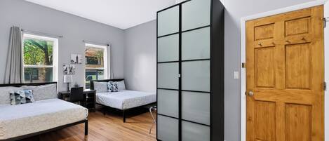 A room with two beds, a desk, a wardrobe, and a door.