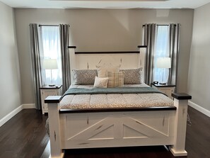Une chambre à coucher avec un lit, des tables de chevet et des rideaux.