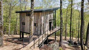 Eine Holzhütte mit Balkon, umgeben von Bäumen.