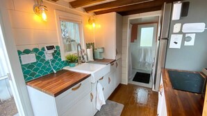 A compact kitchen with white cabinets, a wooden countertop, and a backsplash with green tiles.