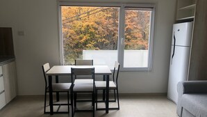 A kitchen with a dining table and chairs, a refrigerator, and a window with autumn foliage view. - IN FRONT OF THE BEAGLE. YOUR PLACE IN USHUAIA (Ushuaia)