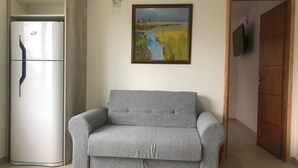 A living room with a grey sofa, a white refrigerator, a painting of a landscape, and a wooden door. - IN FRONT OF THE BEAGLE. YOUR PLACE IN USHUAIA (Ushuaia)
