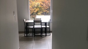 A dining area with a table and chairs, a window with a view of autumn trees, and a tiled floor. - IN FRONT OF THE BEAGLE. YOUR PLACE IN USHUAIA (Ushuaia)