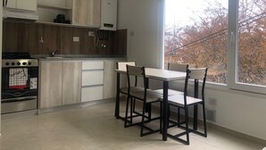 A modern kitchen with wooden cabinets, a built-in oven, and a dining area with a table and chairs. - IN FRONT OF THE BEAGLE. YOUR PLACE IN USHUAIA (Ushuaia)