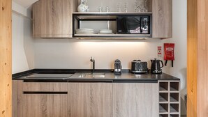 A compact kitchen with a microwave, sink, and storage cabinets.