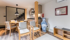 A modern kitchen with wooden cabinets, a dining area with a table and chairs, a large blue vase, and a framed map on the wall.