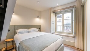 A bedroom with a bed, bedside table, and a window with curtains.