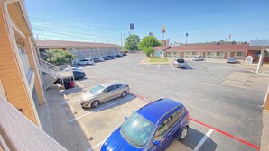 A parking lot with several cars, a McDonald's sign, and a building with a red roof. - Great Western Inn & Suites - Saginaw (Fort Worth)
