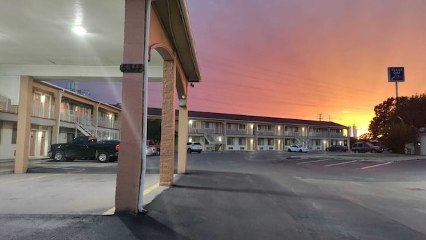 A motel with a gas station attached, featuring a row of rooms and a parking lot. - Great Western Inn & Suites - Saginaw (Fort Worth)