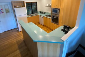 Compact kitchen with modern design, featuring a refrigerator, oven, microwave, and dishwasher.
