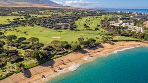 Ein Luftbild eines Küstenresorts mit Golfplatz, Strand und Bergpanorama.