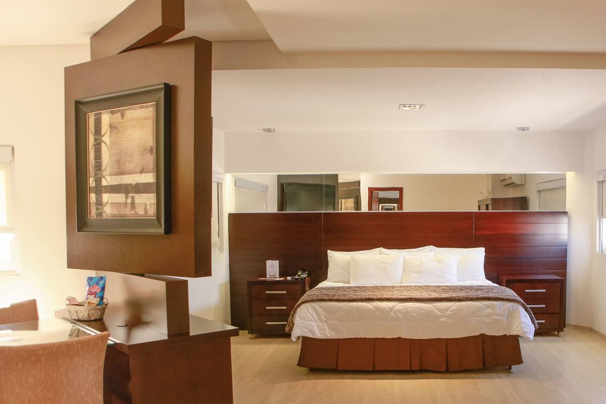 Un dormitorio moderno con una cama grande, cabecera de madera y un escritorio con silla.