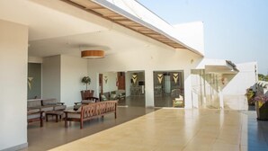 A spacious indoor area with a modern design, featuring a seating area with sofas and chairs, a large open space, and a staircase leading to an upper level. - GoldMen Select Cianorte (Cianorte)