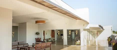 A spacious indoor area with a modern design, featuring a seating area with sofas and chairs, a large open space, and a staircase leading to an upper level.
