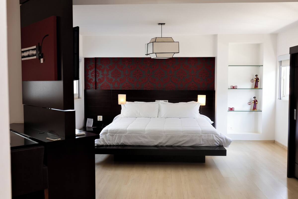 Un dormitorio moderno con cama, mesitas de noche, escritorio y armario.