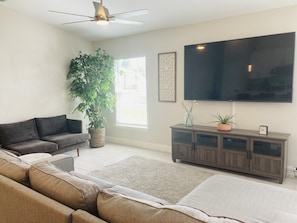 Relax in this stylish living room with a large flat-screen TV, comfortable sofa, and a cozy armchair.