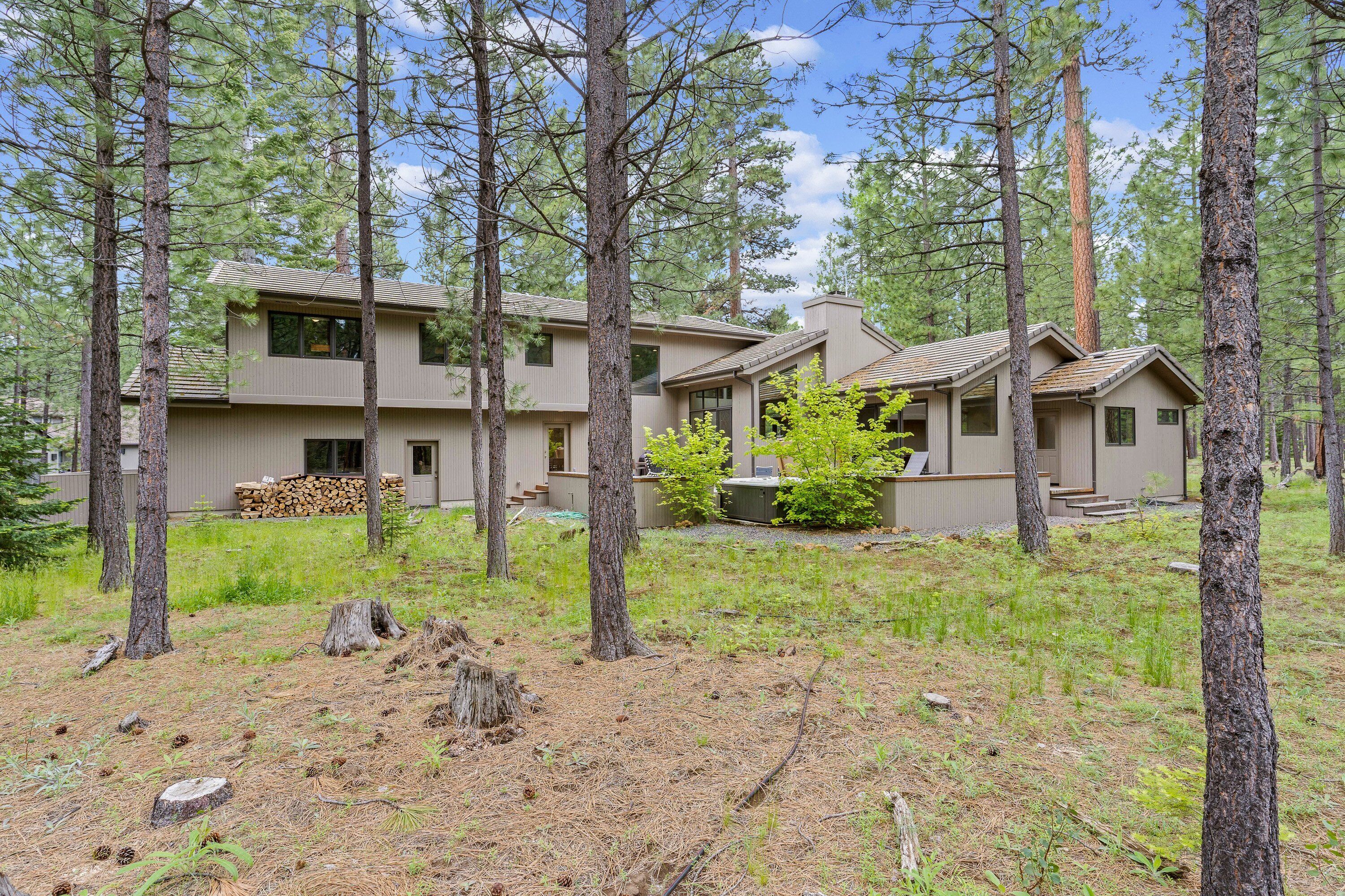 A two-story house surrounded by tall pine trees.