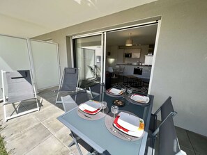 A dining area with a table set for four, a chair, and a view into the kitchen. - Etel - 2-room apartment - 43 sqm - Wifi - Classified 3* (ETEL)
