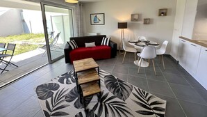 A modern living room with a sofa, coffee table, and dining area. - Etel - 2-room apartment - 43 sqm - Wifi - Classified 3* (ETEL)