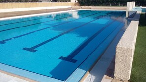 A rectangular swimming pool with clear blue water and lane dividers.