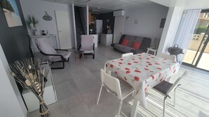 A modern living room with a sofa, a dining table, and a kitchen area in the background. - Nice corner villa located with airco in LES TAMARIS (pool extra fees), 2 bedrooms, 3 stars, Wifi,... (PORTIRAGNES)