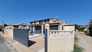 A residential property with a gated entrance, a patio with outdoor furniture, and a garage. - Nice corner villa located with airco in LES TAMARIS (pool extra fees), 2 bedrooms, 3 stars, Wifi,... (PORTIRAGNES)
