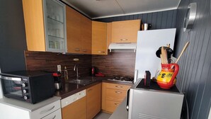 A compact kitchen with wooden cabinets, a microwave, a stove, and a refrigerator. - Nice corner villa located with airco in LES TAMARIS (pool extra fees), 2 bedrooms, 3 stars, Wifi,... (PORTIRAGNES)