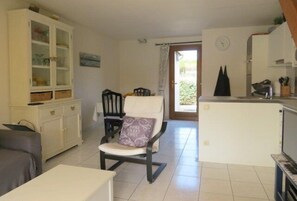 A compact living space with a dining area, a kitchenette, and a seating area with a chair and cushions.