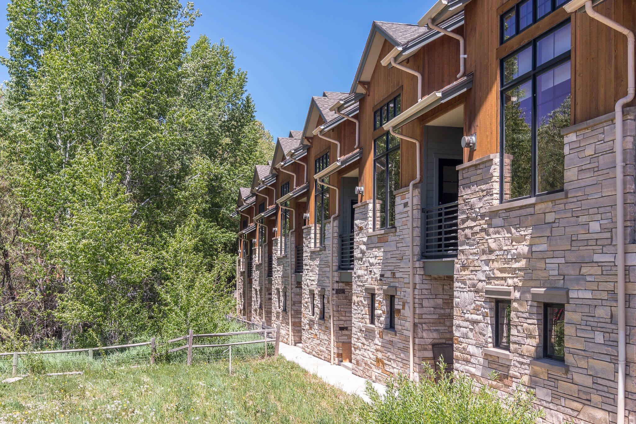 Une rangée de bâtiments en pierre et en bois, dotés de balcons, entourée d’arbres.