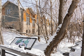 Explore the serene winter landscape surrounding this historic building, set amidst a dense forest and tranquil stream.