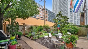 Un espace patio aménagé avec des meubles d’extérieur, des plantes en pot et un barbecue.