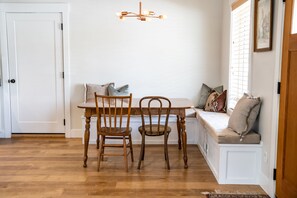 A dining area with a wooden table and chairs, a bench with cushions, and a hanging light fixture.