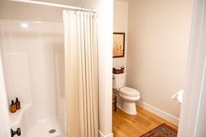 A bathroom with a shower, toilet, and a framed picture on the wall. - The Washburn House - Kid friendly! (Missoula)