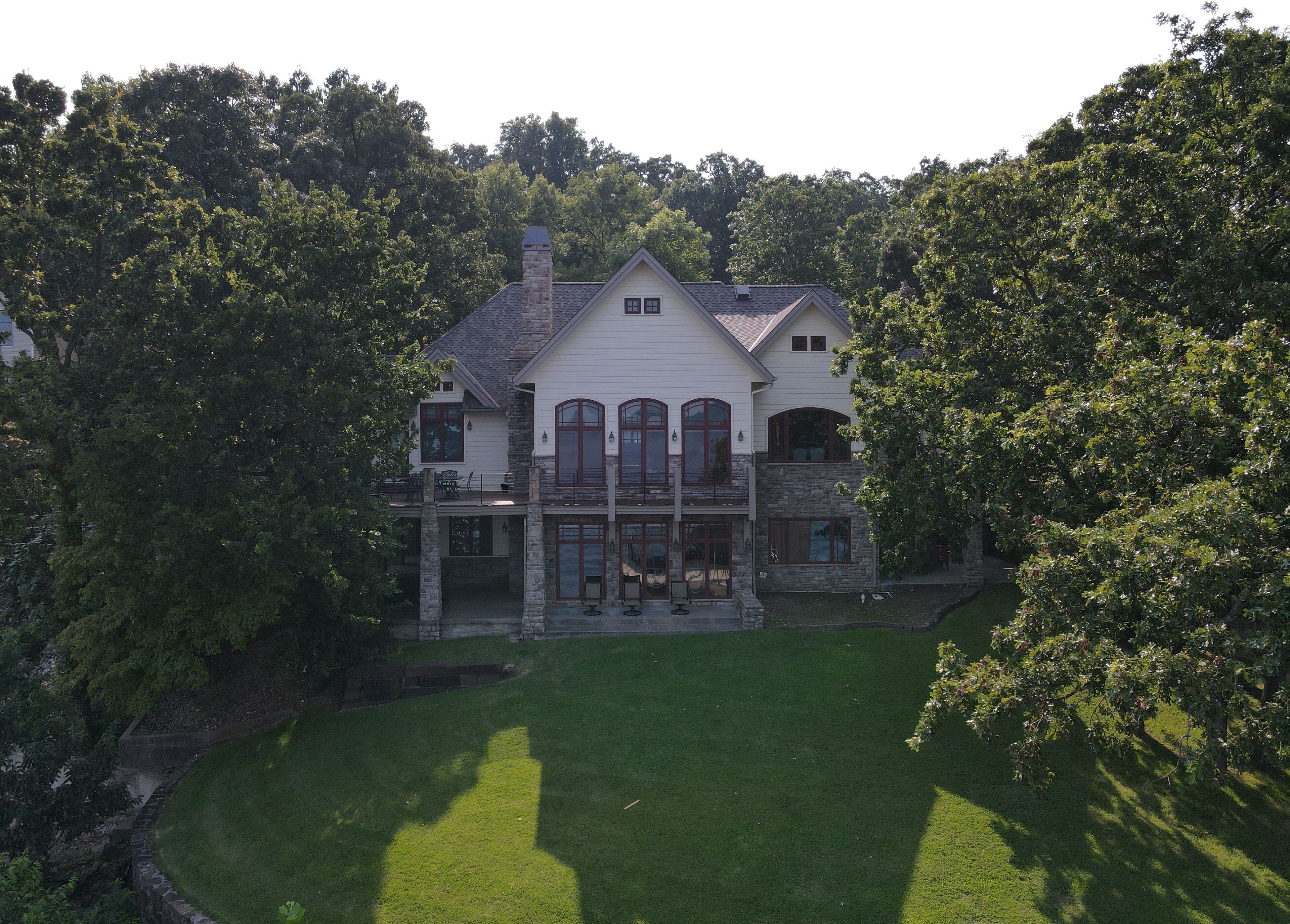 A large, two-story house with a stone facade, multiple windows, and a well-maintained lawn.
