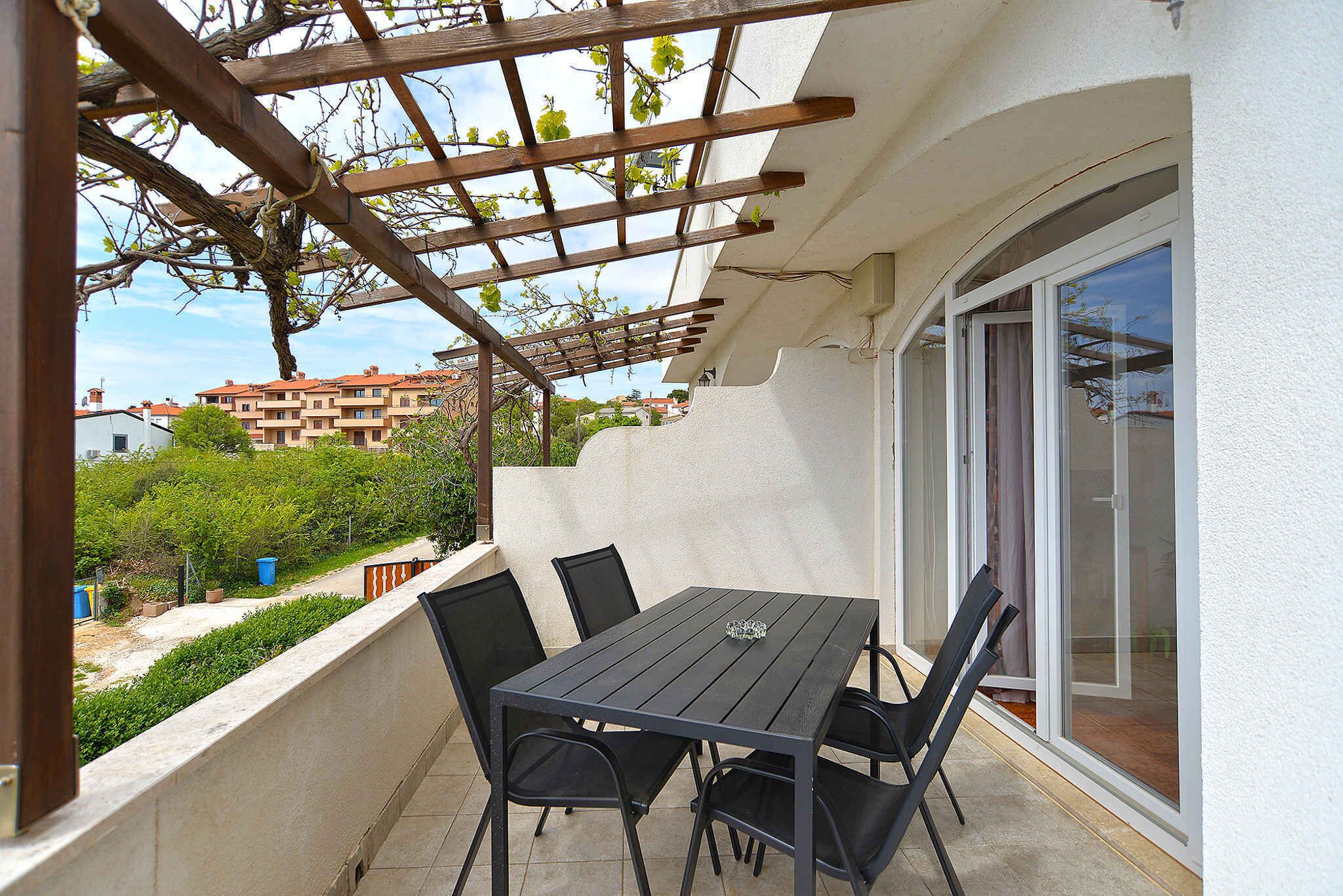 A balcony with a table and chairs, a pergola, and a sliding glass door.