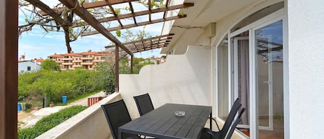 A balcony with a table and chairs, a pergola, and a sliding glass door.
