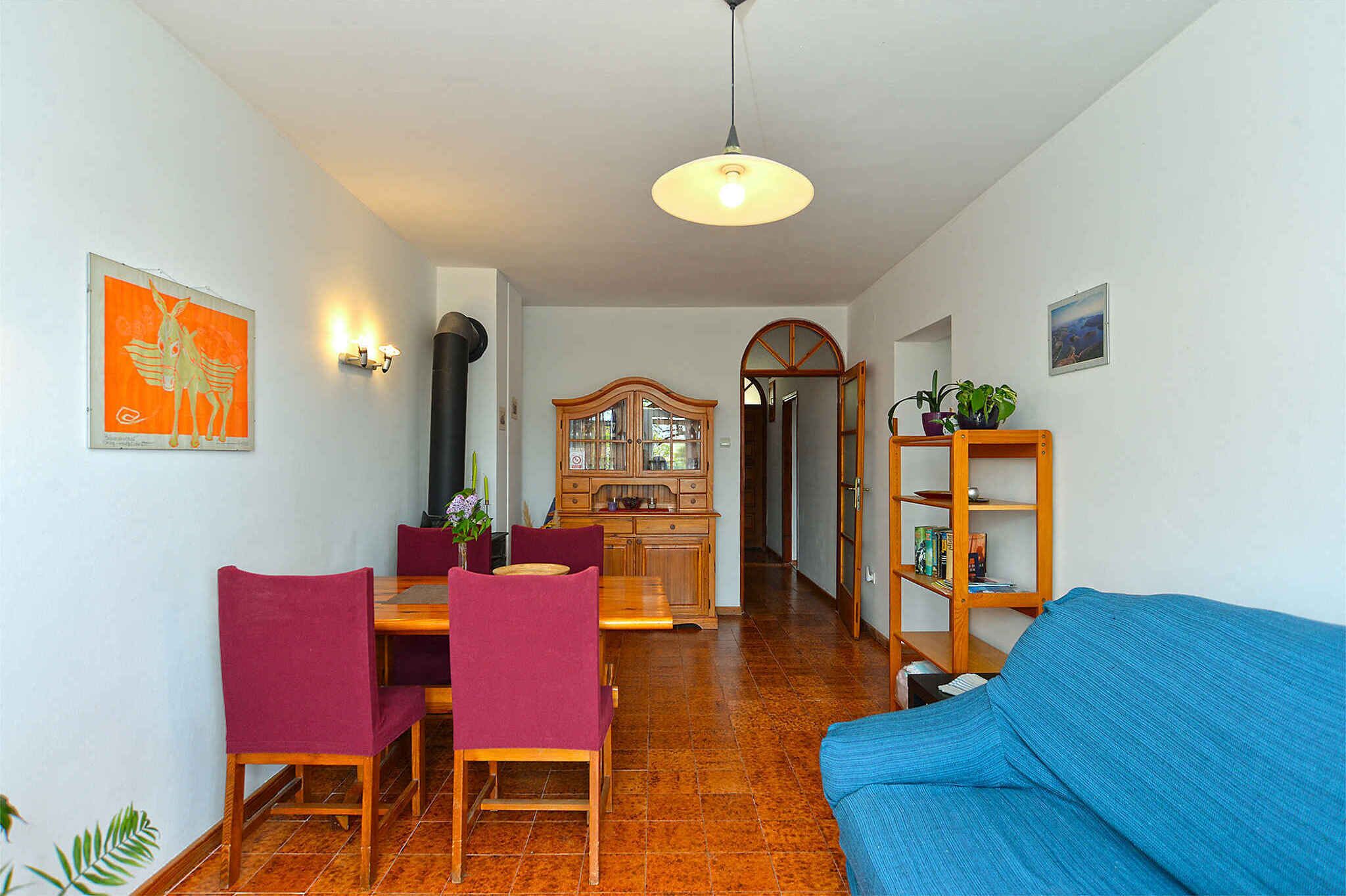Un coin repas avec une table et des chaises en bois, un canapé bleu, un meuble en bois et un luminaire au plafond.