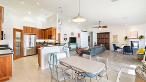 A modern kitchen with stainless steel appliances, a dining area with a table and chairs, and a living room with a sofa and a fireplace. - Hillside Desert House - Hot Tub, Fire Pit and BBQ (Yucca Valley)