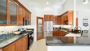 A modern kitchen with wooden cabinets, stainless steel appliances, and a granite countertop. - Hillside Desert House - Hot Tub, Fire Pit and BBQ (Yucca Valley)